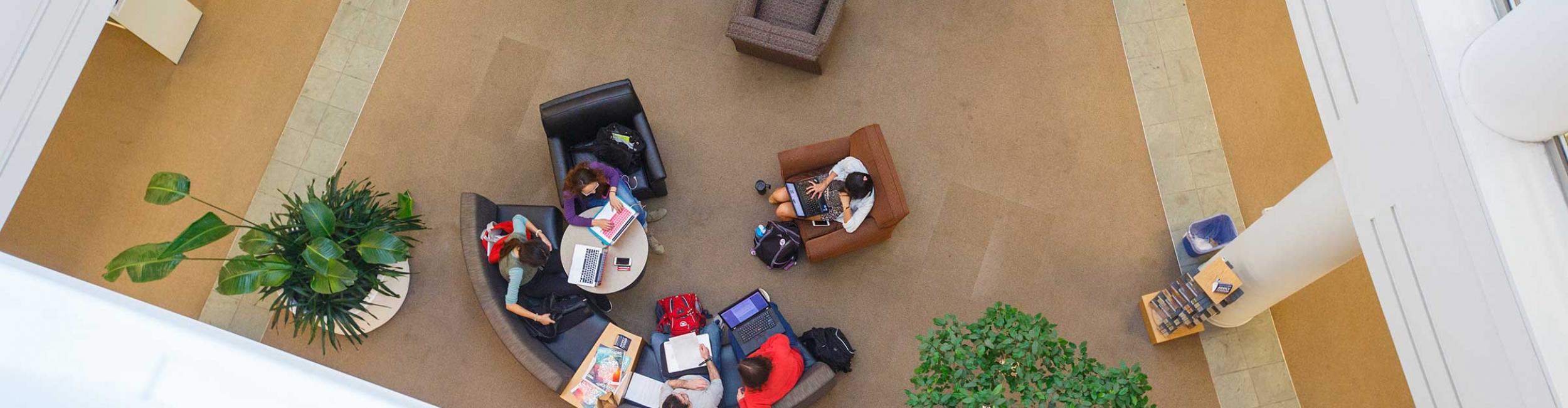 Looking down at a group of students sitting on couches and chairs working on computers