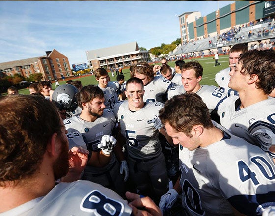 CWRU football team in a huddle at the beginning of a game