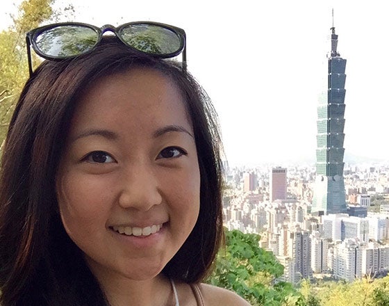 Student standing in front of a large skyscraper while in China