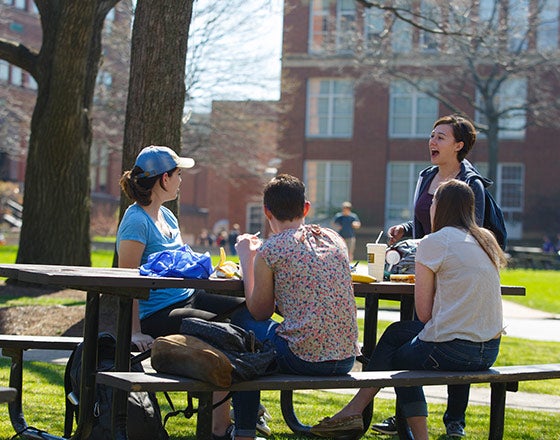 Students sitting at a picnic table outside of their dorms