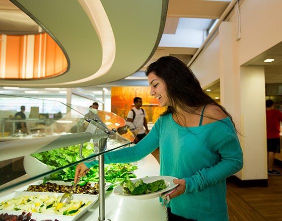 Student grabbing a salad for lunch from the salad bar