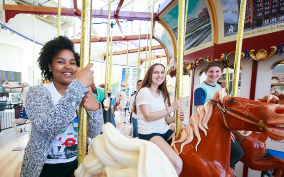history-center-carousel three students sitting on carousel horses at the Cleveland History Center