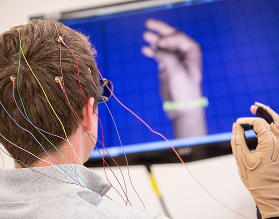 Student with sensors attached to his head moving a robotic hand with his mind