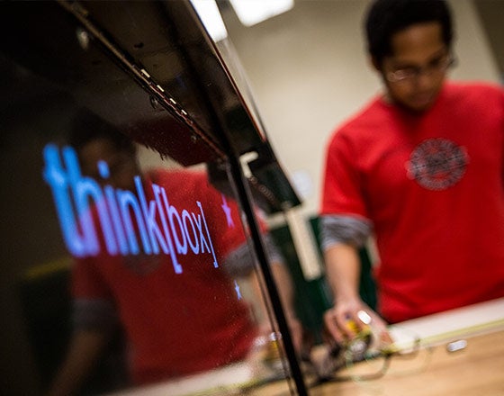 thinkbox logo on monitor with a student working in the background