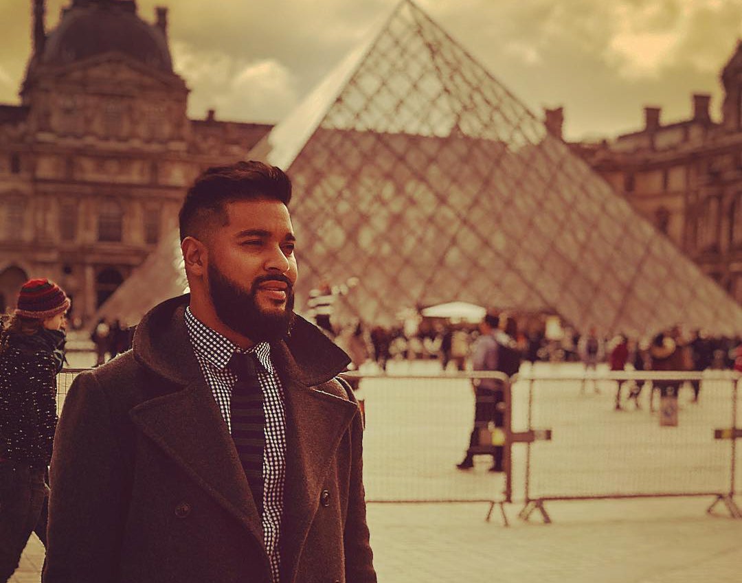Student looks off camera with the Louvre in the background