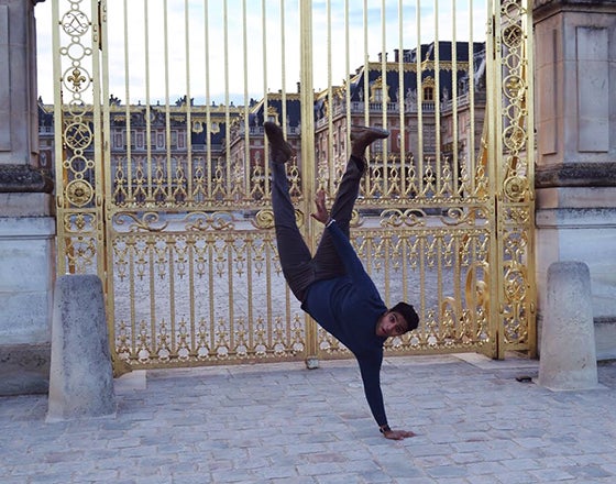 Student does a one-handed handstand in front of castle gates