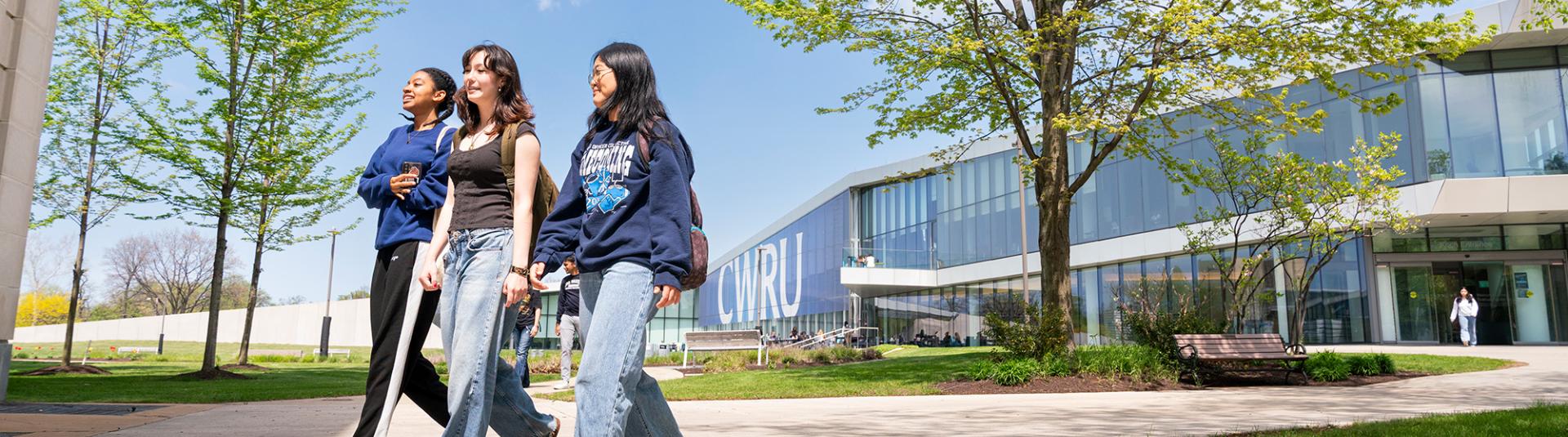 A group of three students walk together on campus.