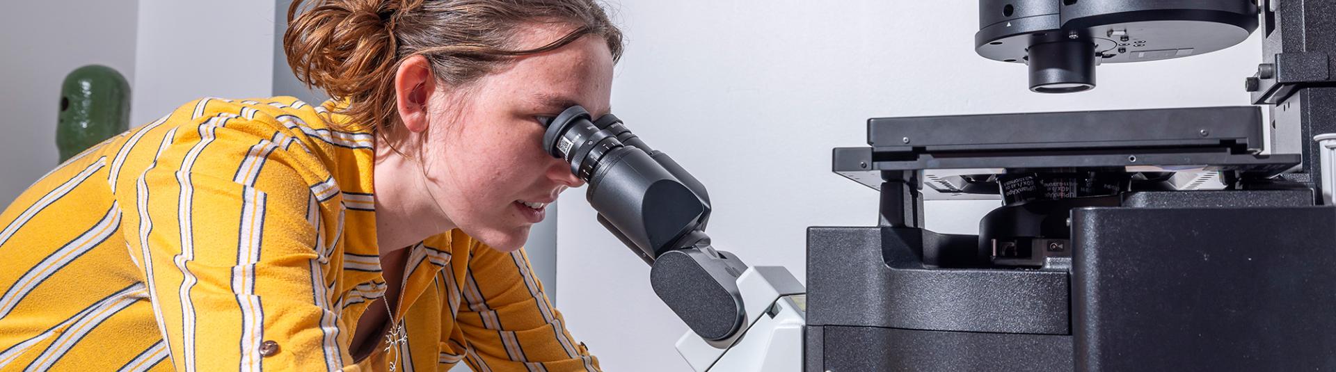 Student looking into microscope. 