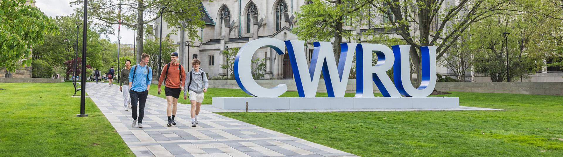 Students walking on campus near large CWRU letters.