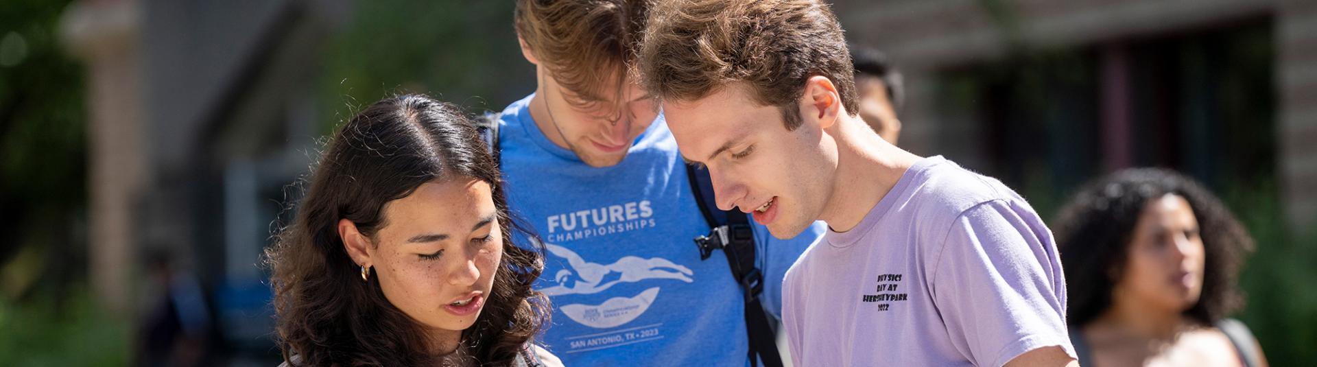 Three students looking at a folder.