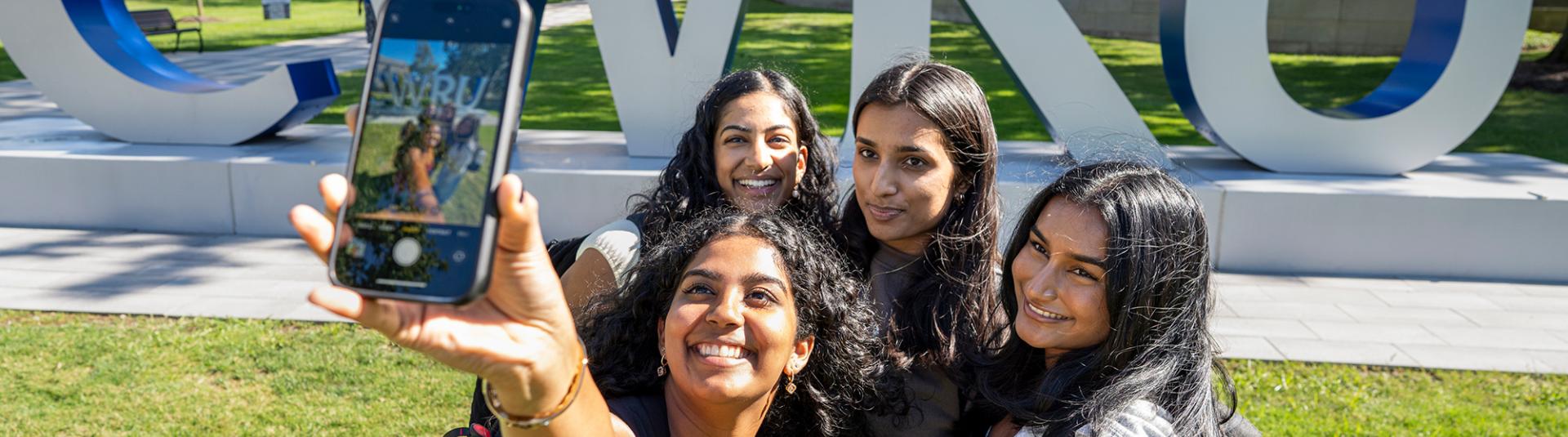 Group of students posing for a photo with the CWRU letters on campus.