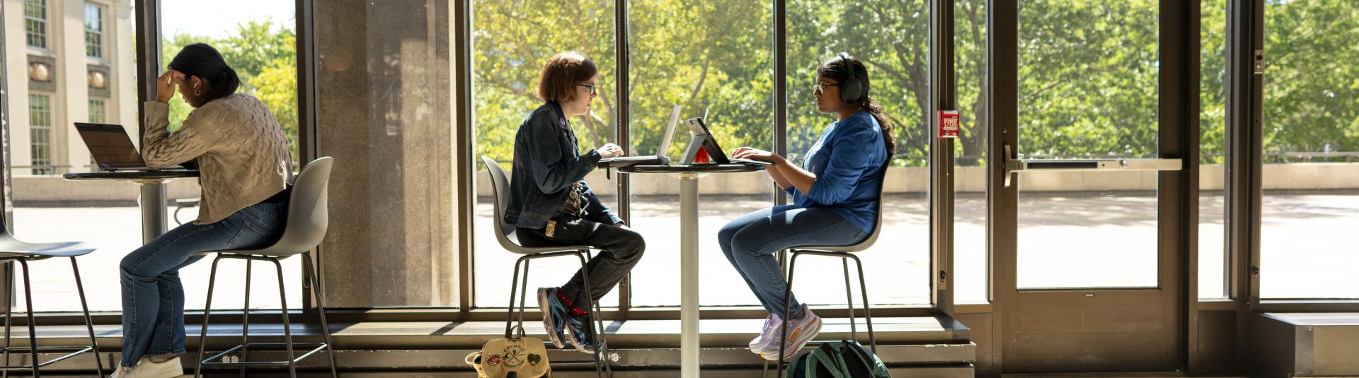 Two people sitting at a high top table in front of a window