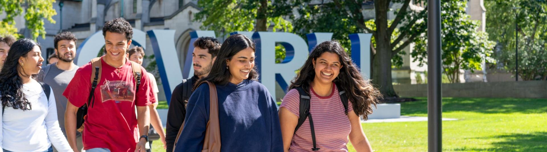 Students smile as they walk past the CWRU letters on their first day of classes.