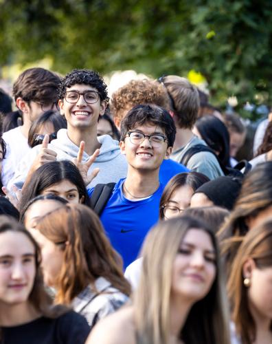 Students smile and wave as they walk towards the Homecoming Tailgate celebration.