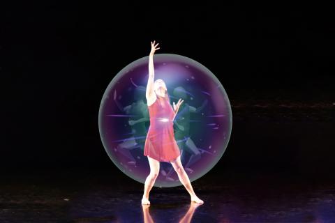 Student dancer reaches upward from holographic bubble