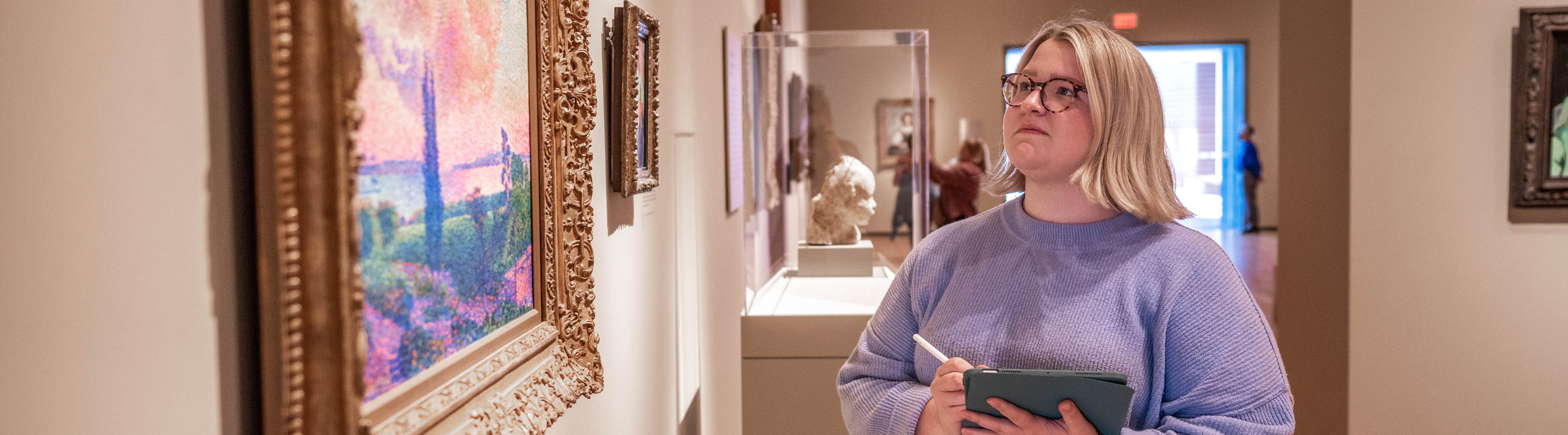 a white female student studying a painting