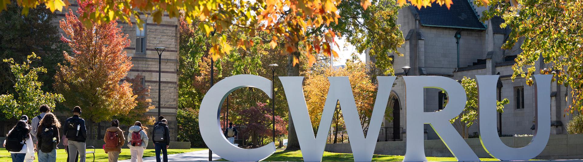 Students walk past the CWRU sign near the Quad in the fall.