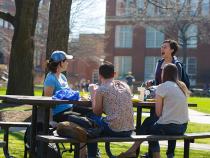 Students sitting at a picnic table outside of their dorms