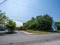 Wide photo of a road leading up to a parking garage, a blue sculpture is to the right side of the road