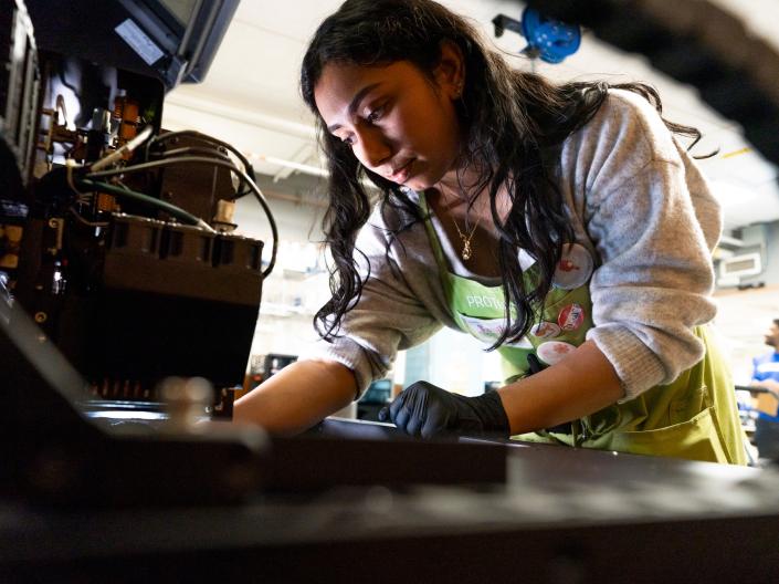 A student works on equipment for a project in Think[box].