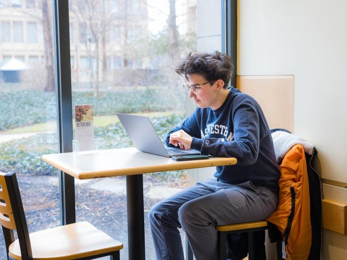 Student on laptop sitting at a table.