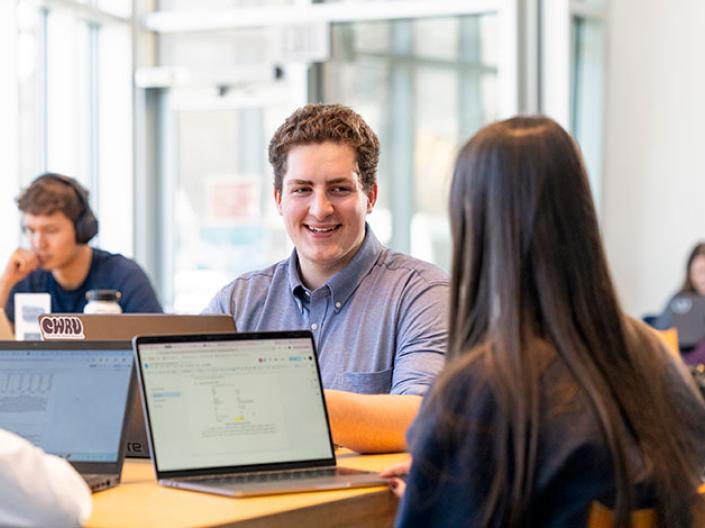 Person sitting across from another person with laptop open