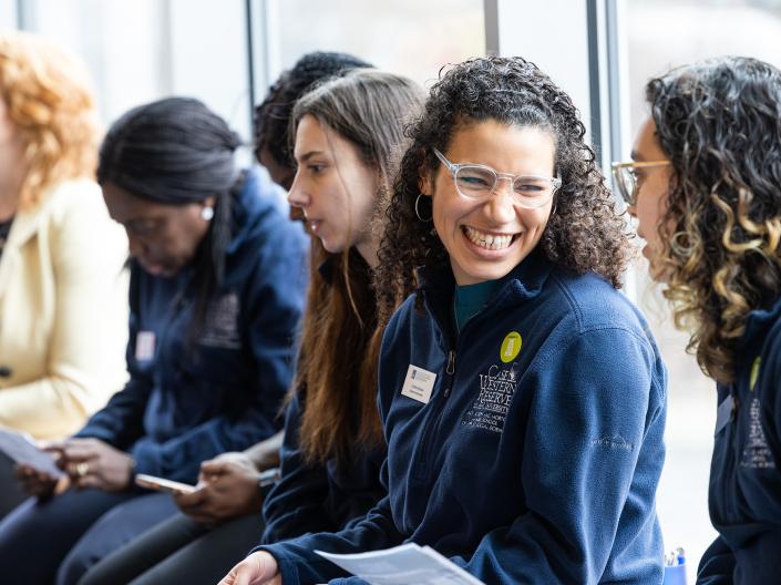 Individuals wearing CWRU jackets laugh together during an Open House presentation.