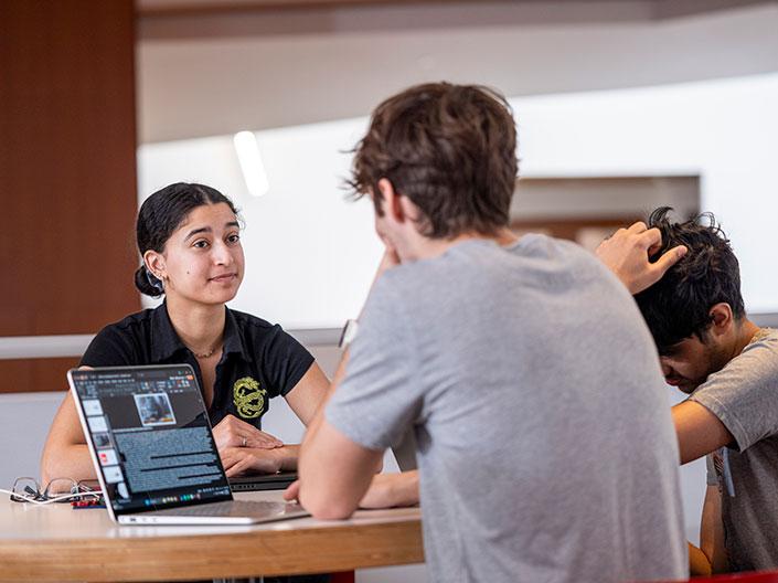 Two people in front of computers talking