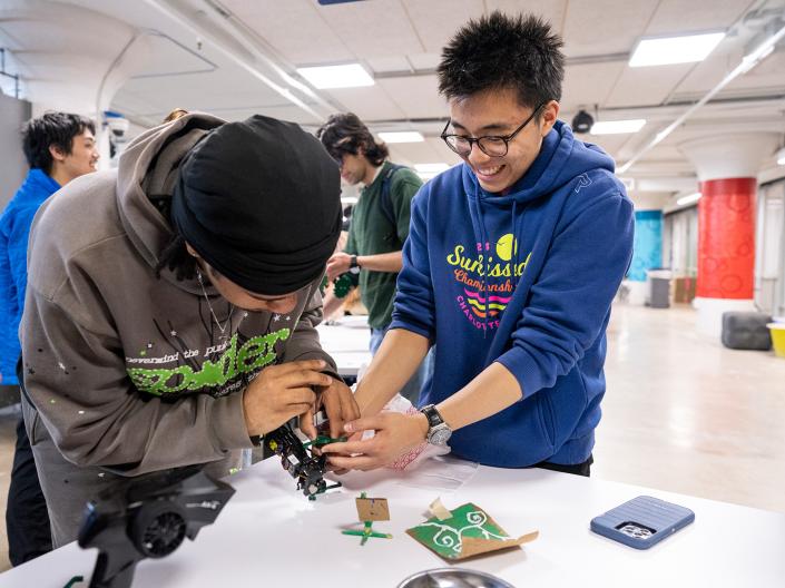 Students laugh as they work on a robotics model together in Sears think[box].