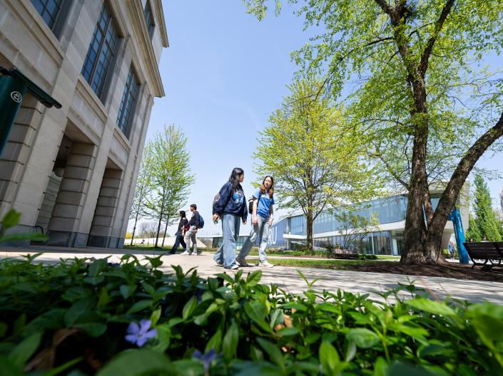 Students walking on sidewalk near campus building.