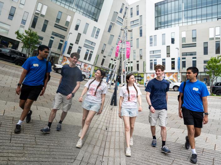 Students walking near reflective building.