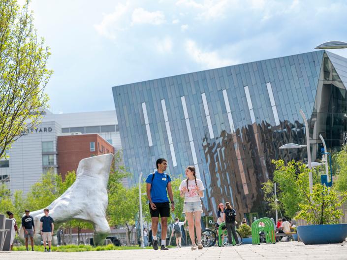 Students walking near hand sculpture