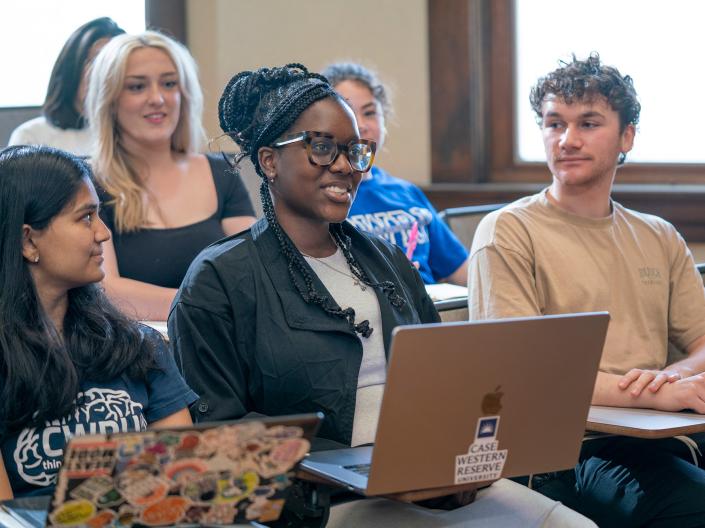 Students in class look and smile towards the middle student as she speaks.