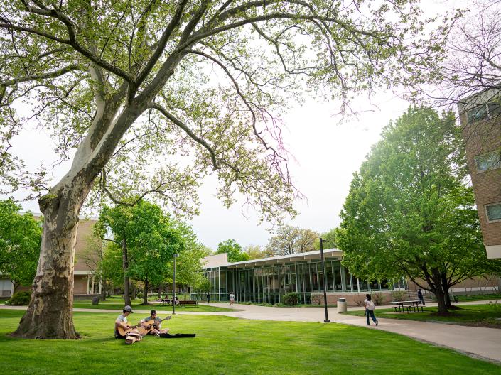 Students sit on the lawn in the North Residential Village playing guitars or walking to class.