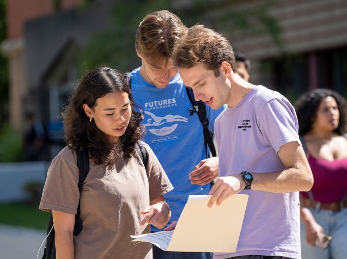 Three students looking at a folder.