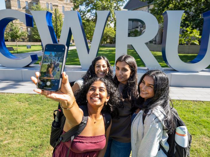 Group of students posing for a photo with the CWRU letters on campus.