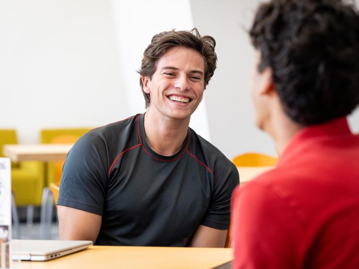 Male student talking to another student.