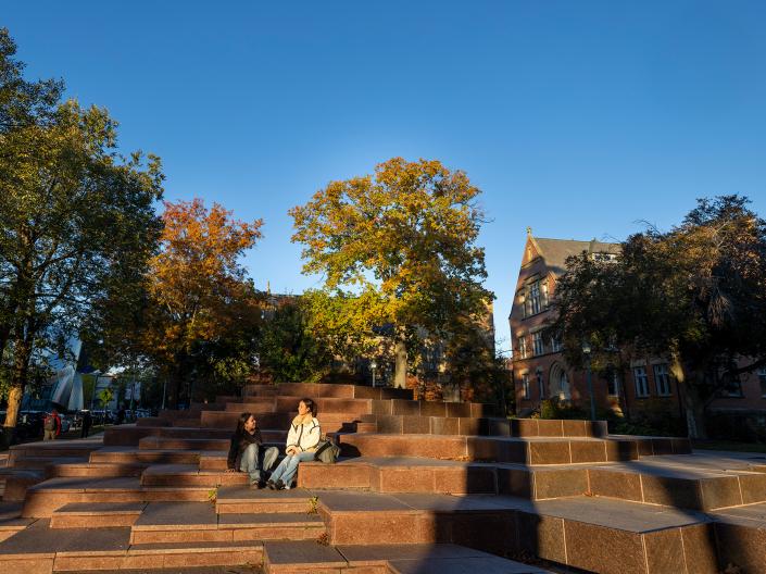 Students sit on a sculpture steps around campus.