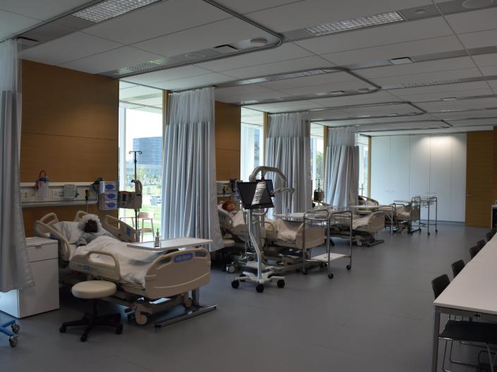 Hospital beds line the walls with simulation dummies in the Center for Nursing Education, Simulation, and Innovation.