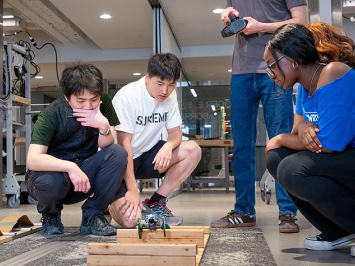 three students looking at an engineering prototype