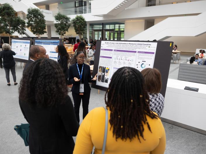 A student presents her medical research board to a crowd of people.