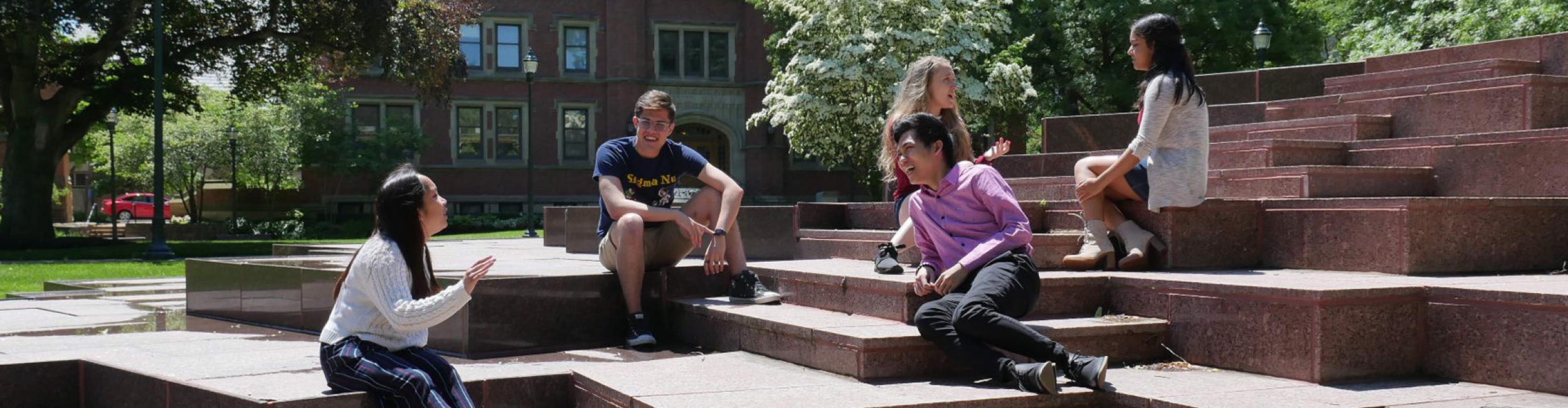 students sitting on a fountain talking