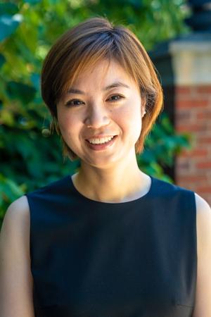 Asian woman smiling in front of trees