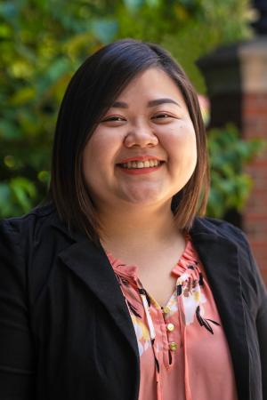 Asian woman smiling in front of trees