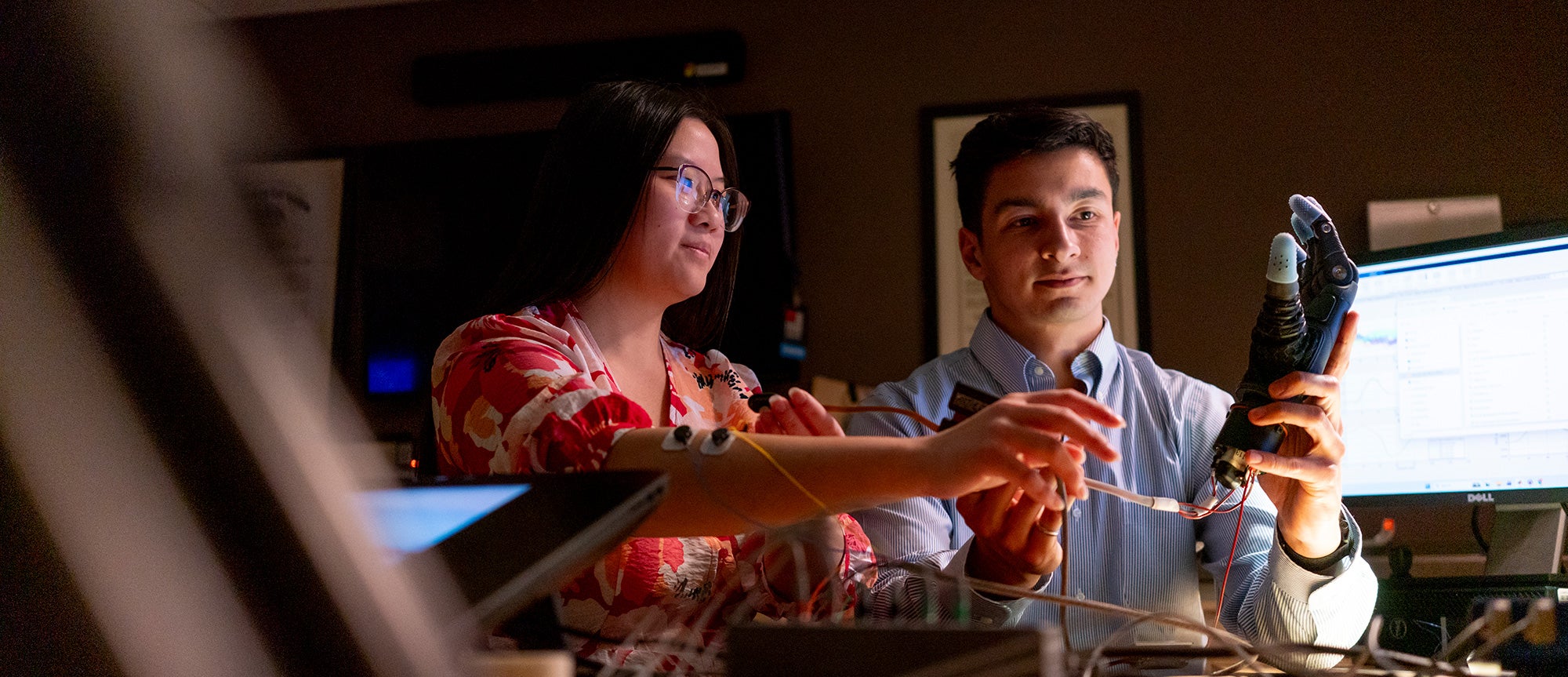 Two students work together on configuring a prosthetic limb.