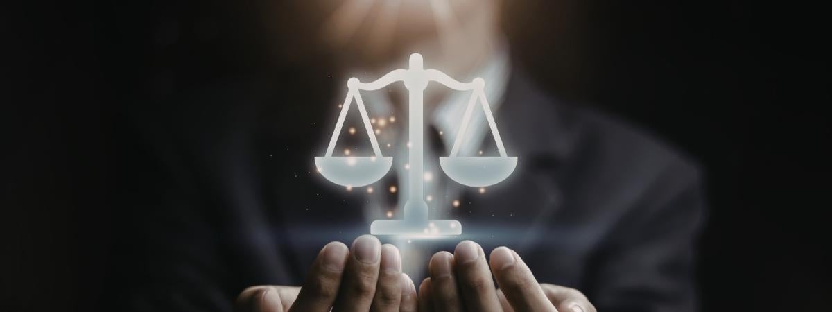 An individual cupping their hands around a floating graphic of law scales.
