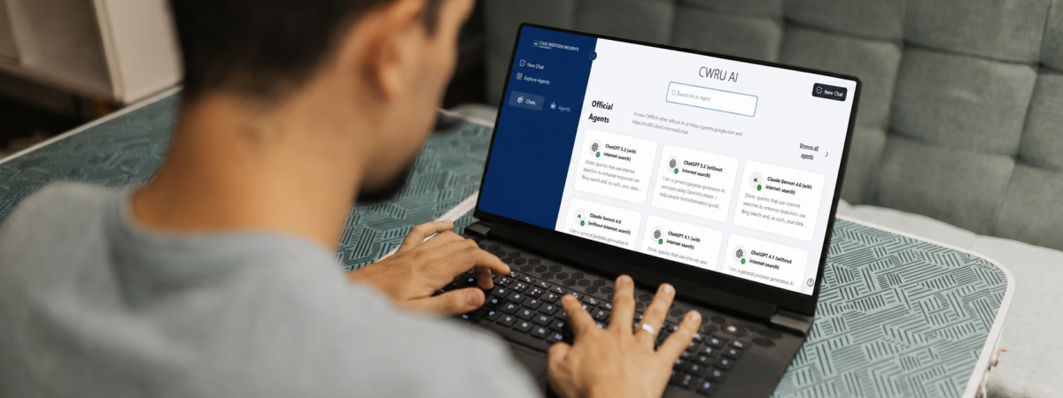 A person typing on a laptop showing the CWRUAI interface while sitting at a desk with glasses nearby.