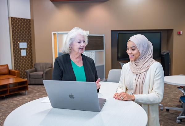 A student and faculty member work together on a laptop in the Kelvin Smith Library.