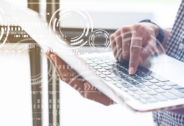 Someone holding a laptop and typing with white gear icon graphics overlaid on top.
