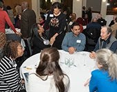 Photo of a diverse group of people enjoying dinner and conversation at the Linsalata Alumni Center